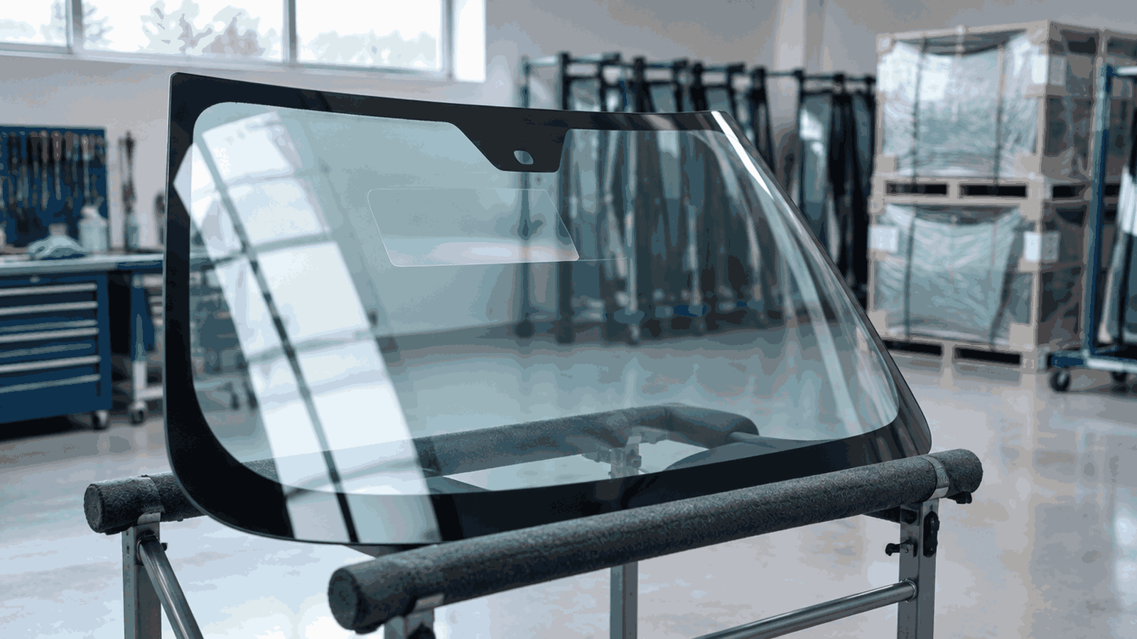 UK glass shop windscreen on a rack with soft workshop light suggesting a HUD projection zone, no readable text